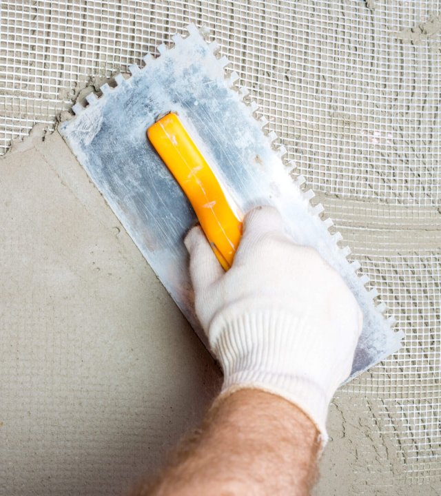 Embedding the fiberglass mesh on the thermal insulation boards and then smoothing the adhesive mortar with a notched trowel.